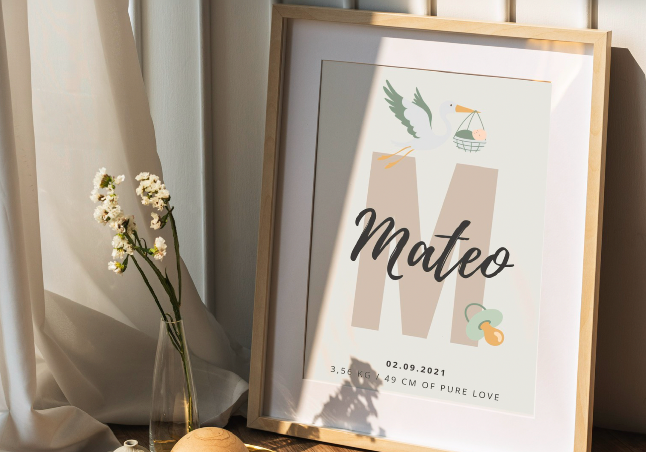 Framed print with 'Mateo' and baby details on a table with a vase of flowers.
